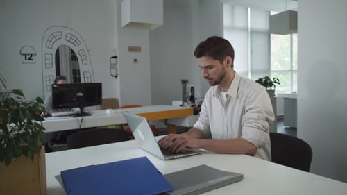 Young Casual Professional Man Working In Modern Open Plan Office Space.
