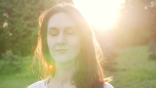 Young Woman Relaxing in Field at Sunset