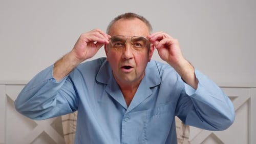 Senior Man Takes Off Glasses Surprised Indoors