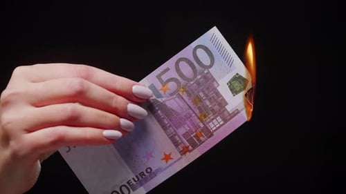 Hand Holding and Burning 500 Euro Banknote