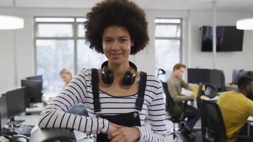 Portrait of smiling african american creative businesswoman sitting by desk in modern office