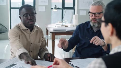 Multiethnic Male Architects Discussing Papers with Female Colleague