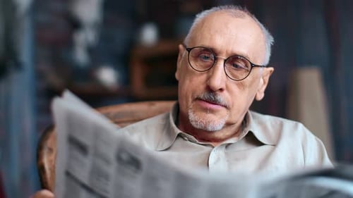 Senior Adult Reading Newspaper Indoors, Close Up