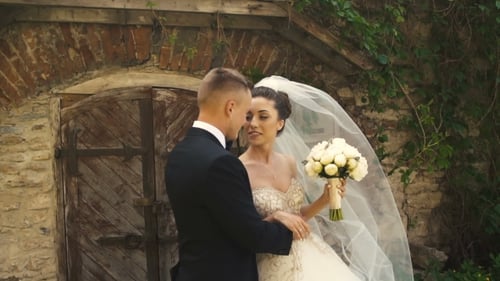 Bride and Groom Embrace Beside Stone Building