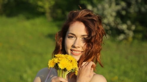 Smiling Woman Holding Yellow Dandelions in Nature