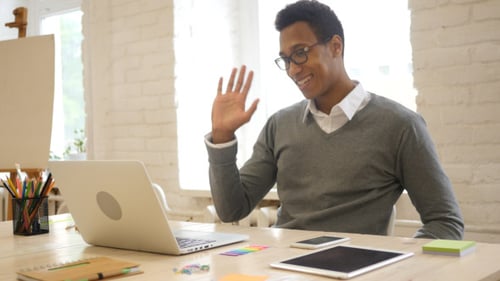 Man Using Laptop for Video Call at Desk