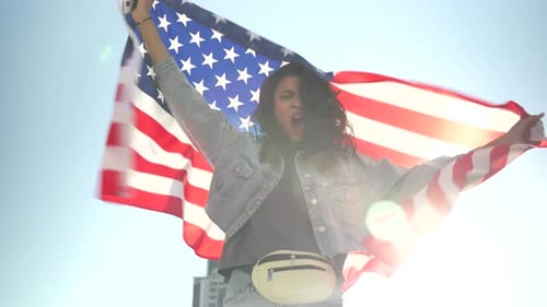 Woman Holding American Flag Against Blue Sky