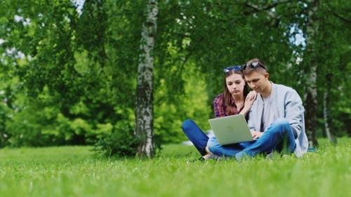 Man And Woman Relaxing Together In The Park, Working With Laptop