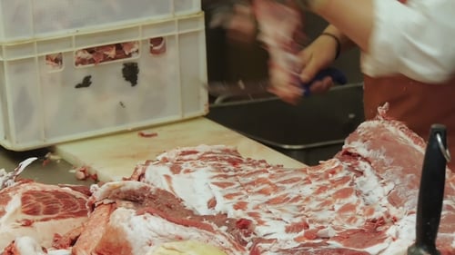 Worker Cutting Raw Meat With Knife in Workplace