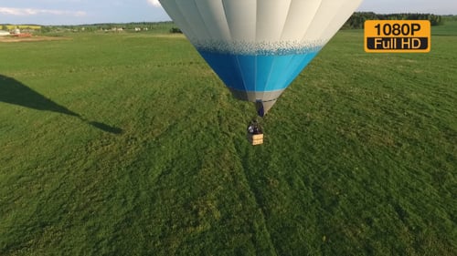 Hot Air Balloon Glides Over Green Landscape
