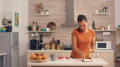Woman Spreads Butter on Toast in Kitchen