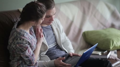 Young Couple Using Laptop on Couch at Home