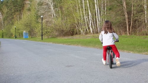 Little Girl Riding Her Balance Bike In The Park