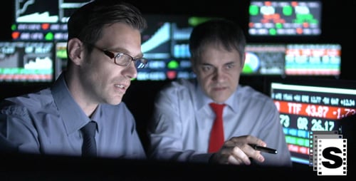 Serious Men Analyze Financial Data in Dark Office