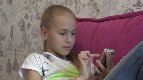 Girl Uses Mobile Phone while Relaxing at Home