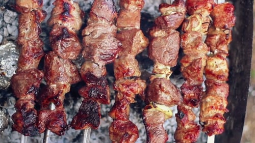 Mann nimmt Spieße mit gekochtem Fleisch vom Grill ab