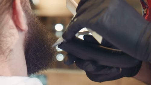 Barber Shaping Beard with Trimmer in Barbershop