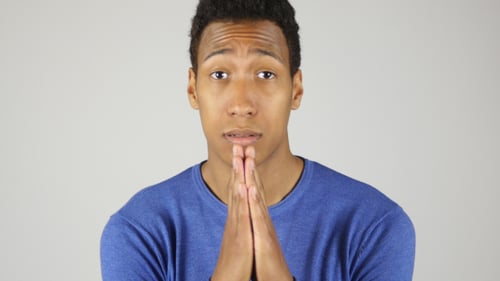 Young Man Looking Sad, Hands Clasped in Plea