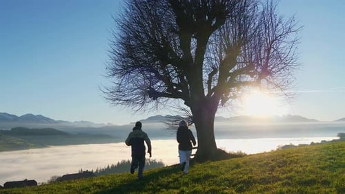 Two Young People Hiking Together in Panoramic Mountain Landscape Standing on Top of Viewpoint