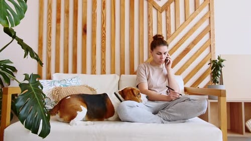 Woman on Couch Talking on Phone with Dog