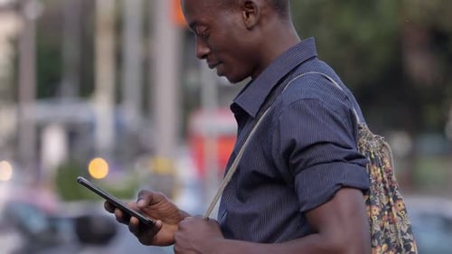 carefree black ma typing on smartphone in the street- profile- slow motion