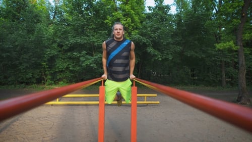 Muscular Man During His Workout In Park. Dips, Exercise Chest And Triceps.