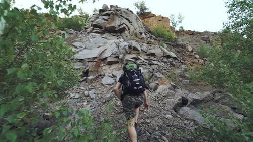 tourist with sports equipment is climbing a rock and viewing a beautiful place from height