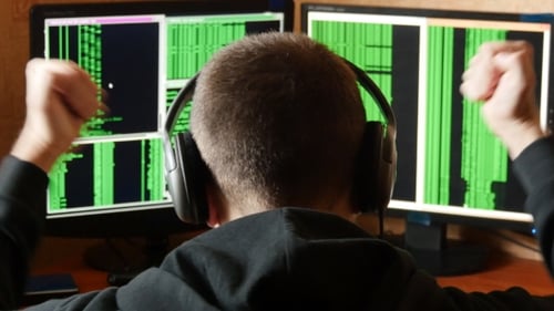 Young Adult Works with Code on Computer Screens