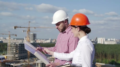 Construction Workers Review Blueprints at Building Site