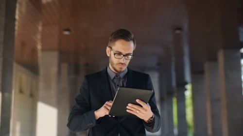 Man in Suit Uses Tablet in Urban Setting