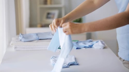 Adult Folding Clean Baby Clothes at Home
