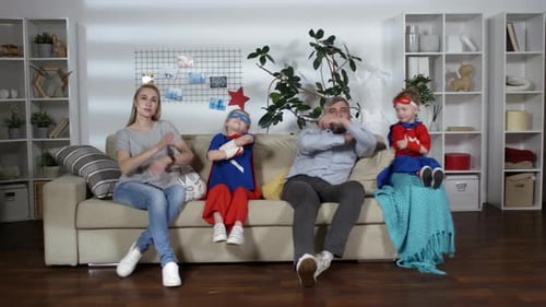 Family Dressed as Superheroes Posing on Couch