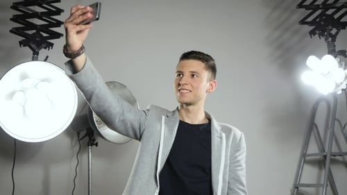 Smiling Man Takes Selfie in Studio Setting
