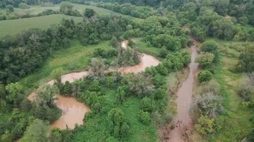 Nachwirkungen eines Sturms in einem Tal im Mittleren Westen. Schlammiges Bachwasser bahnt sich seinen eigenen Weg durch das Tal.
