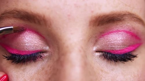 Nahaufnahme der Augen einer jungen Frau beim professionellen Schminken