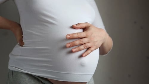 Pregnant Woman Holding Baby Bump and Lower Back