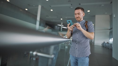 Stylish Hipster At The Airport With a Smartphone In Hand.