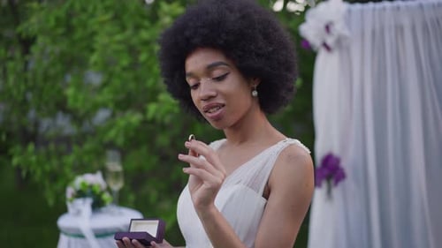 Woman in White Dress Examining Wedding Ring Outdoors