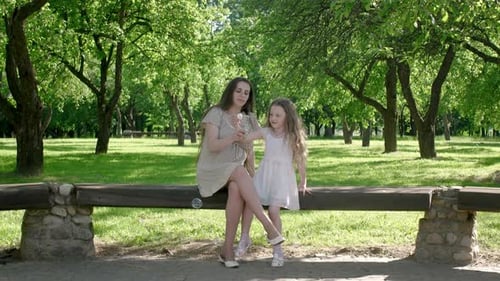 Mother and little girl daughter child blowing soap bubbles