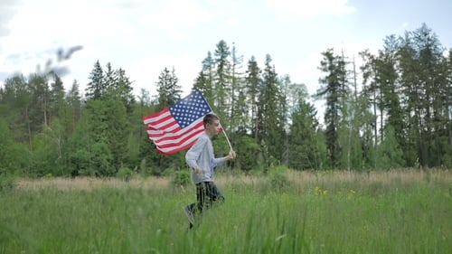 Boy Runs with American Flag in Grassy Field