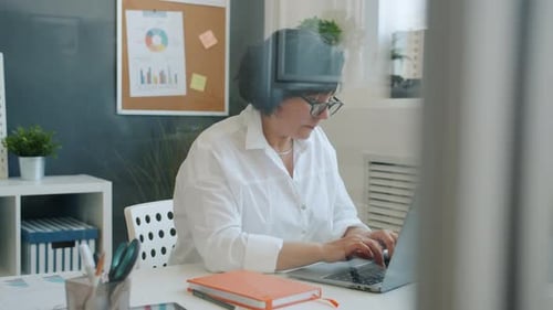 Ernsthafte Geschäftsfrau, die am Laptop tippt, konzentriert sich auf die Unternehmensarbeit im Büro