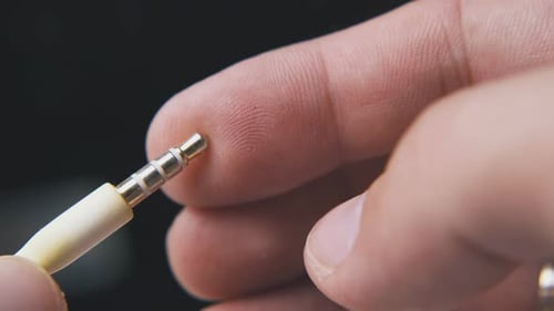 Hand Holding an Audio Cable with Jack