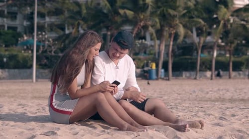 Couple Relaxing on Beach with Smartphone