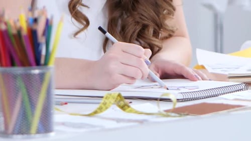 Fashion Designer Draws Sketches for a New Collection and Smiles Sweetly. Close Up