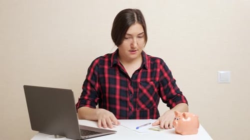 Lady Plans Budget Inserting Dollar Bill Into Piggy Bank