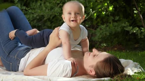 Happy Smiling Baby Boy Lying on Mother in Park