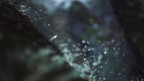 Water Droplets and Spray Flowing and Splashing on Rock at Waterfall. Close Up.