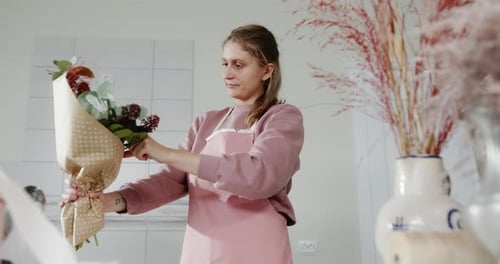 Femme fleuriste arrangeant un bouquet dans une boutique