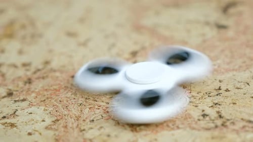 Spinner à main blanc à tourner sur une table en bois