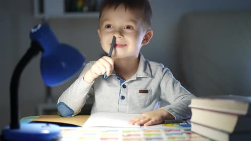 Boy Writes Under Blue Lamp at Night